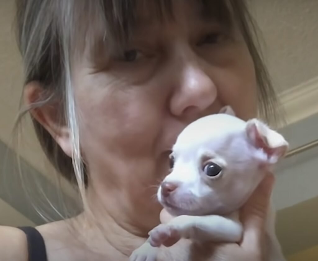 Frau kuschelt mit kleinem weißen Hund.
