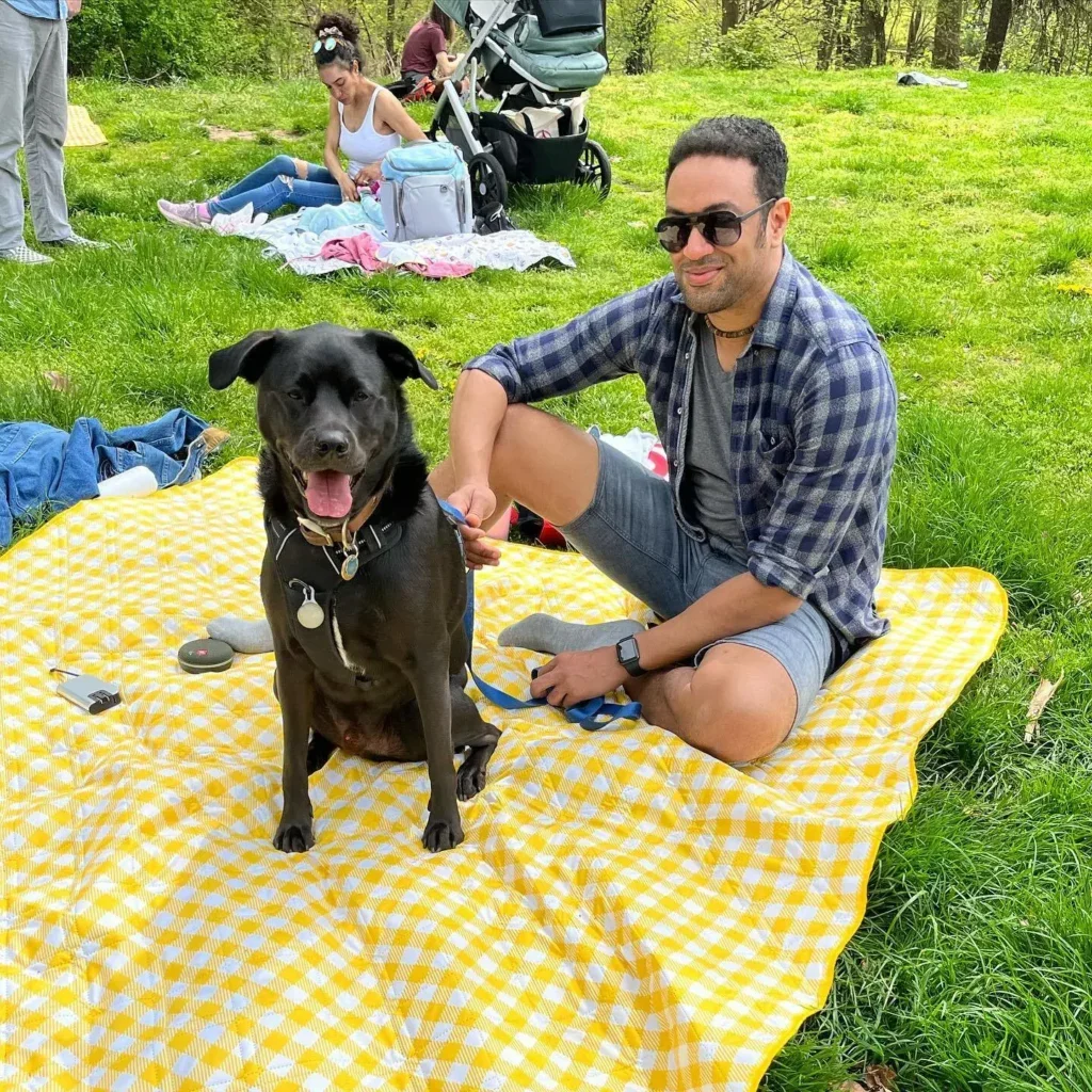Mann und Hund entspannen auf Picknickdecke im Park.