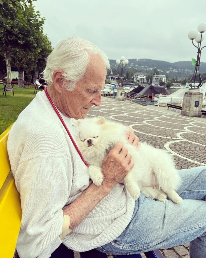 Senior hält entspannt einen kleinen Hund.