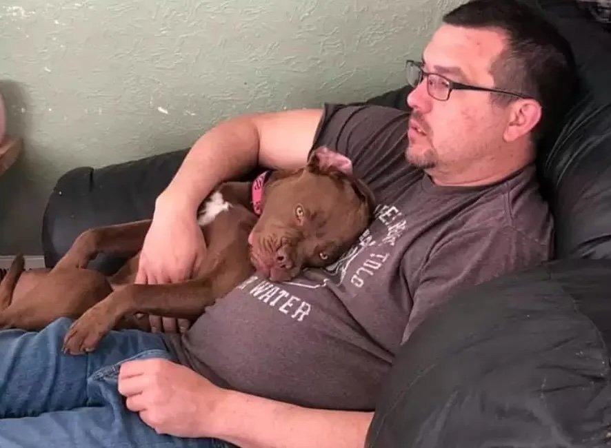 Mann entspannt mit schlafendem Hund auf Couch.